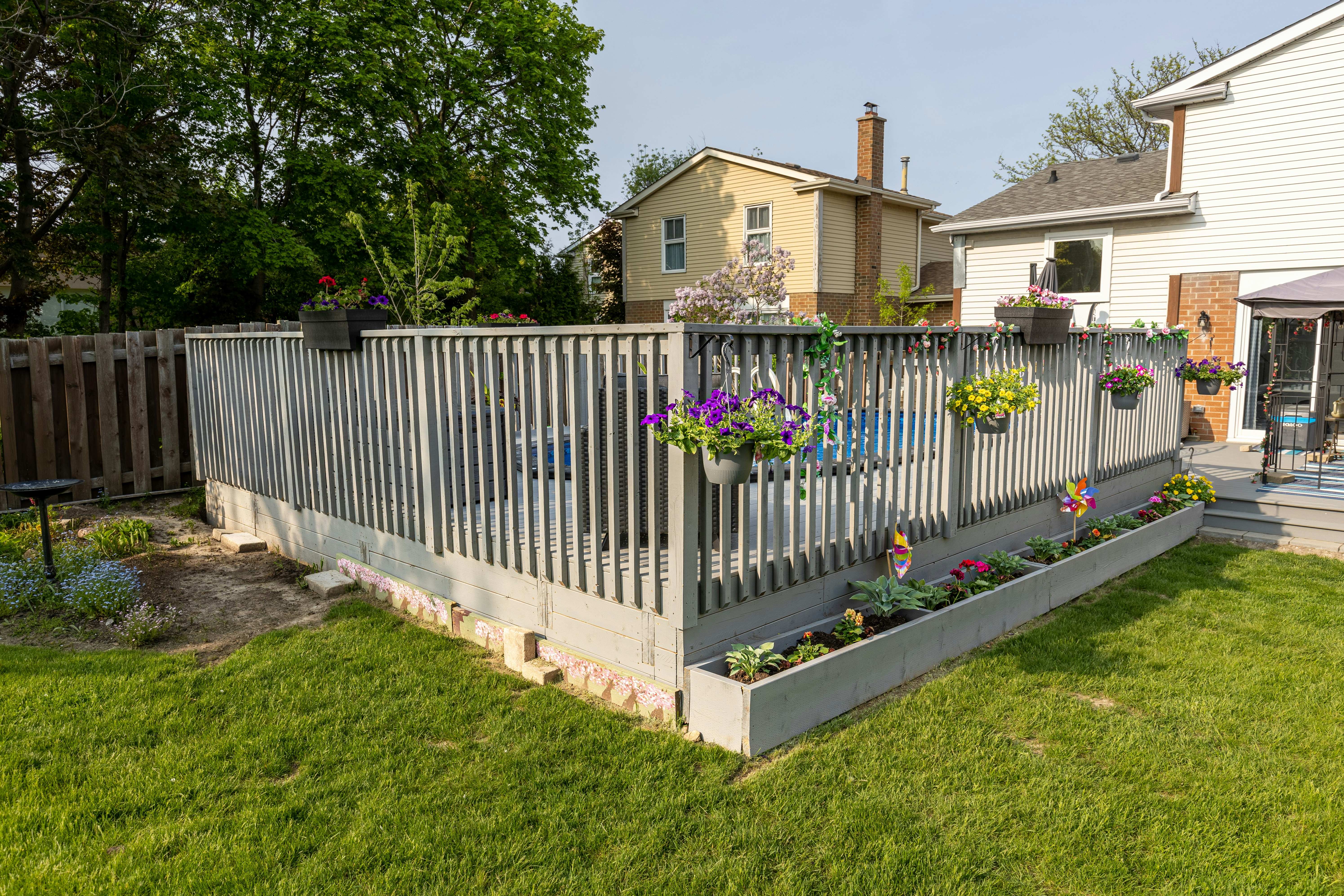 Beautiful residential picket fence with decorative flower baskets and landscaped garden bed