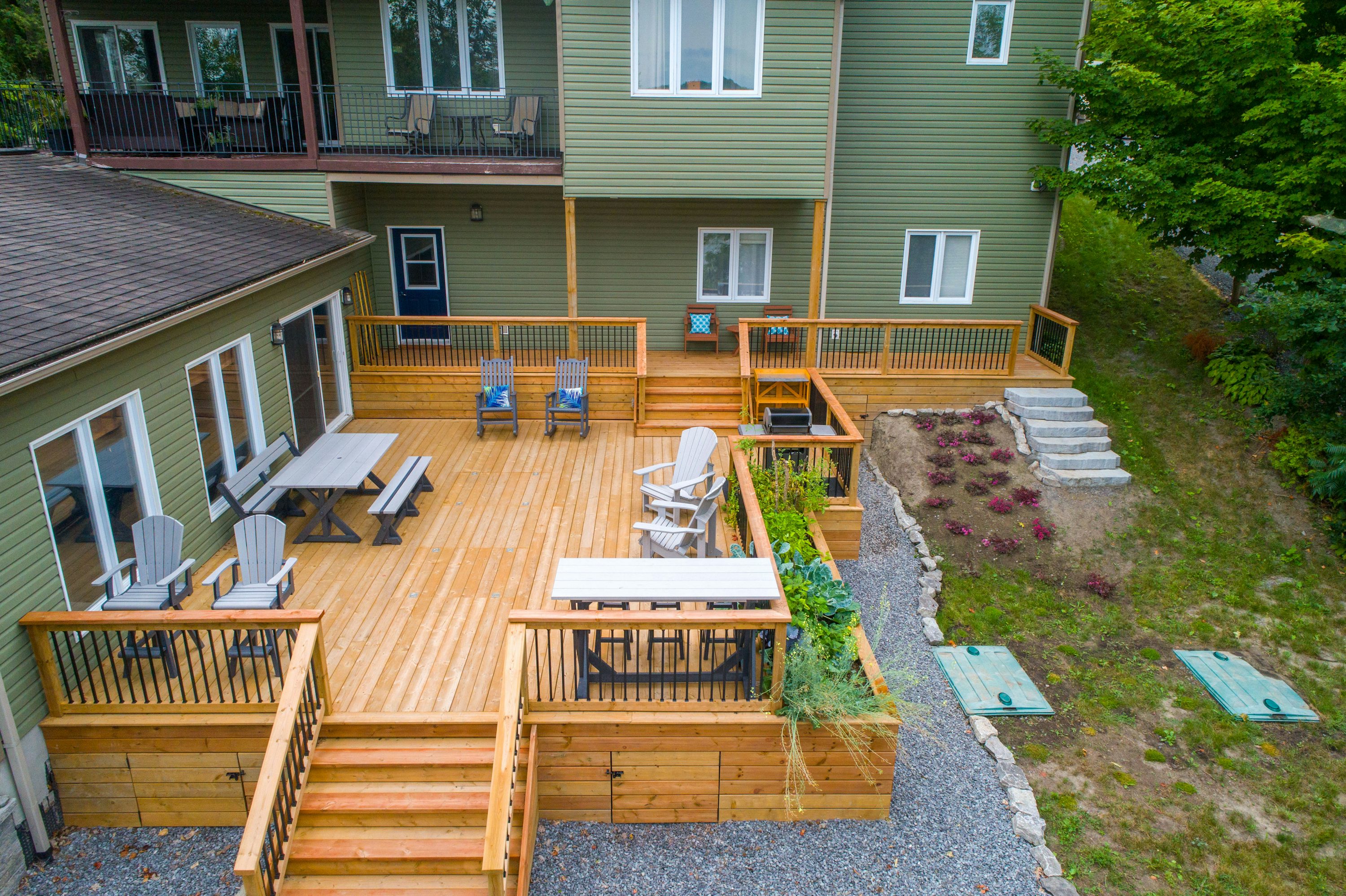 Luxury multi-level cedar deck with multiple seating areas, dining spaces, integrated planters, and professional landscaping