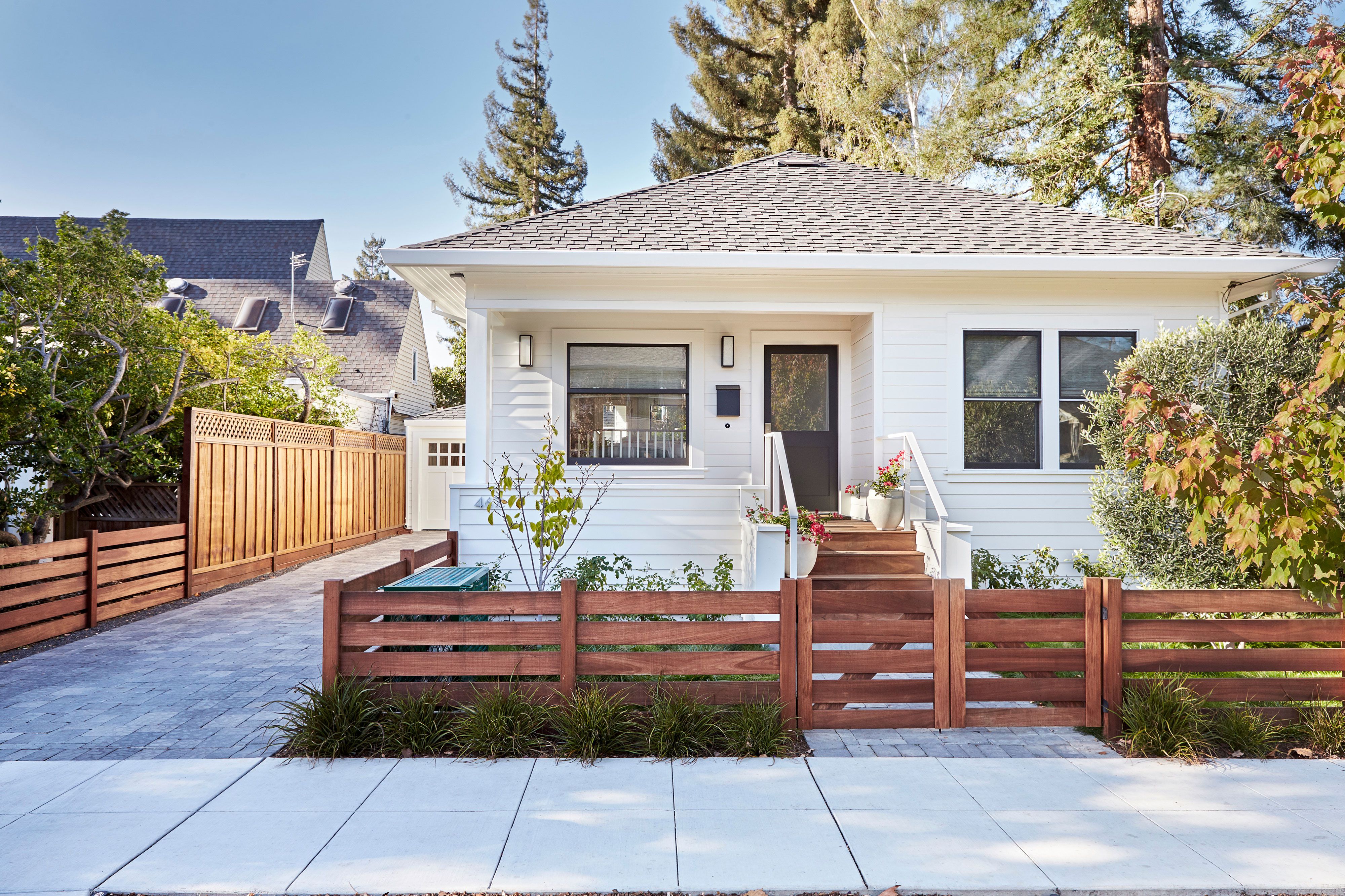Modern horizontal slat cedar fence with clean lines complementing white craftsman-style house and professional landscaping